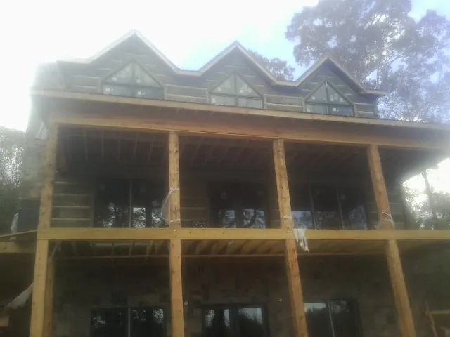 Dormers and porch framing on a large log home under construction — Roof Coating work by our crew in Loon Lake