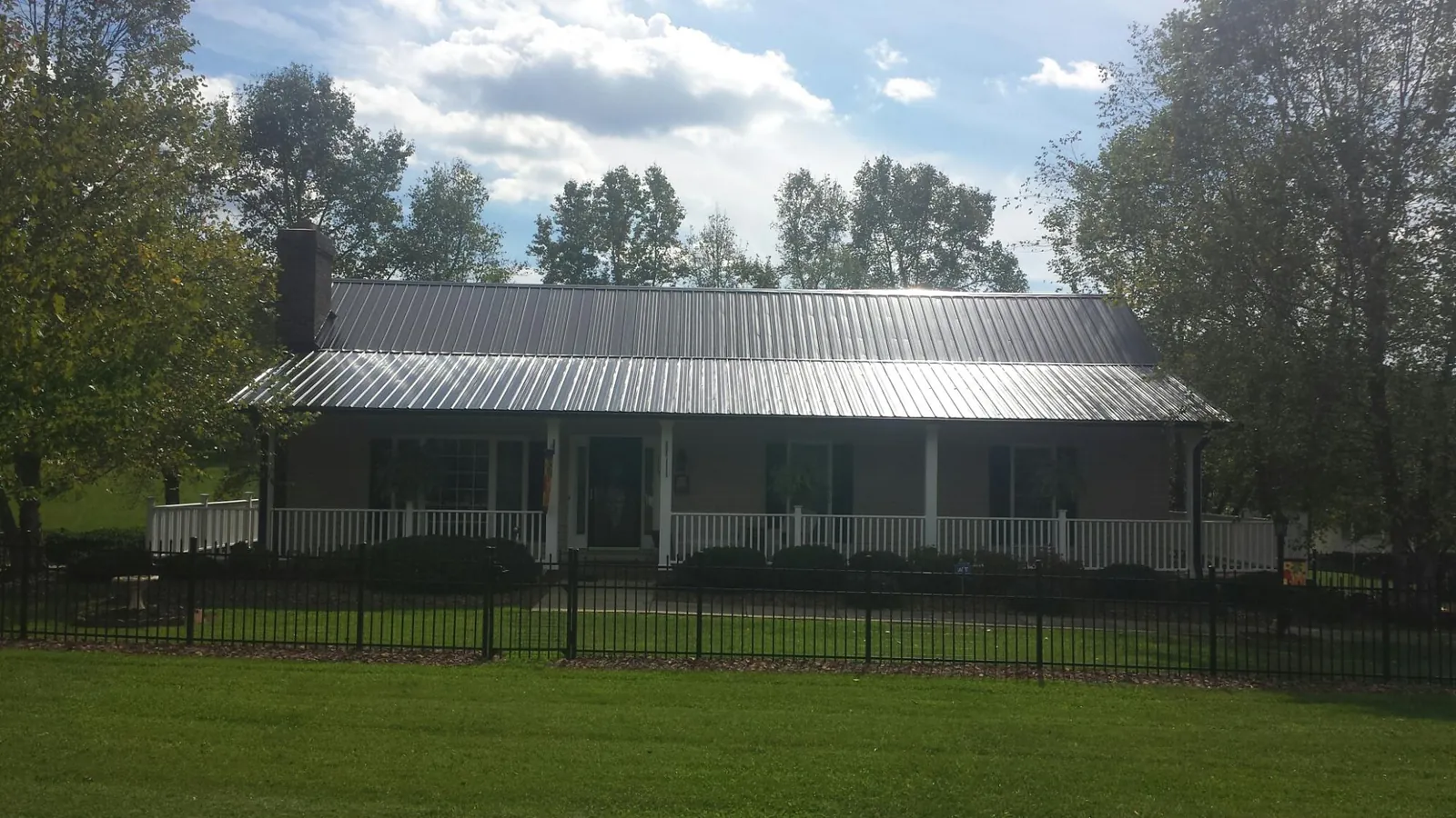 Gray metal roof on a brick ranch with a full width front porch — Gutter Guard Installation work by our crew in Loon Lake