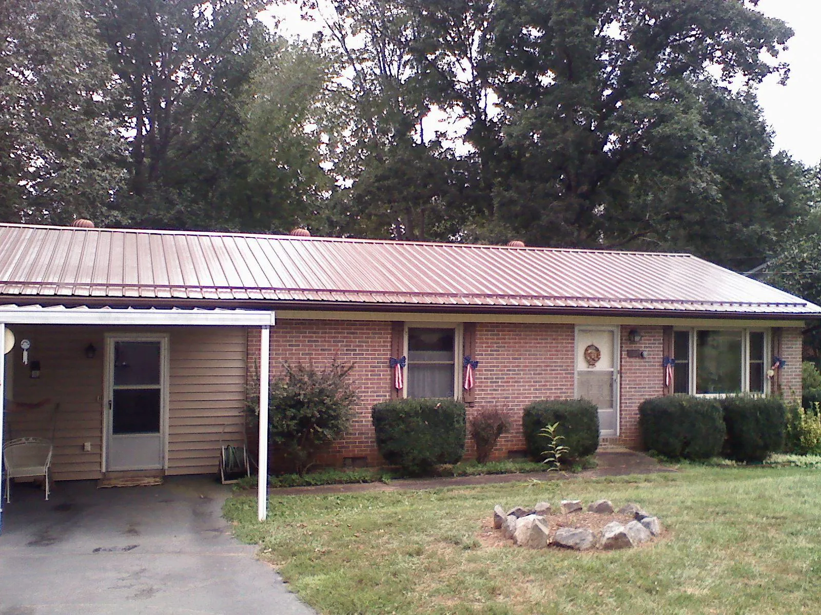 Bronze metal roof and carport on a brick ranch home — Roof Repair work by our crew in Loon Lake