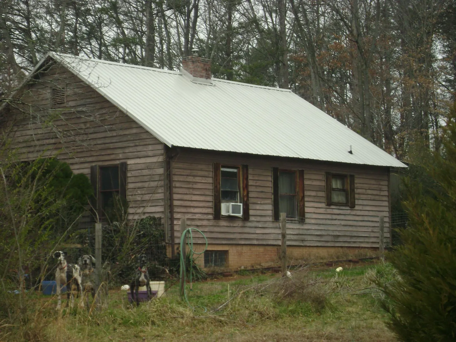 White metal roof on an old wood sided farmhouse, from a Metal Roof Installation job in Loon Lake