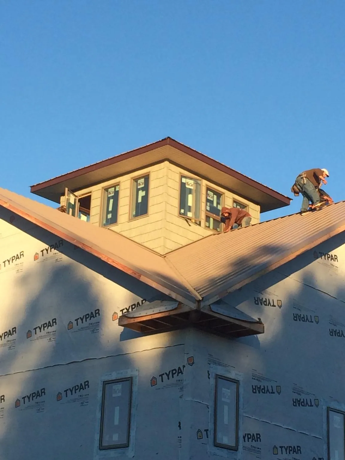 Roofers working around a rooftop cupola on a new metal roof at sunset — Roof Waterproofing in Loon Lake by Roofing Brothers